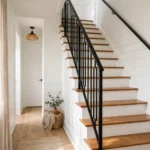 Bright hallway staircase after a budget makeover with white risers, oak treads and a black handrail