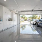Bright modern garage with a glossy light-grey epoxy floor, two parked cars and white storage cabinets