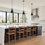 Modern kitchen with a navy blue waterfall-edge kitchen island, wooden overhang seating side, four oak bar stools and black pendant lights